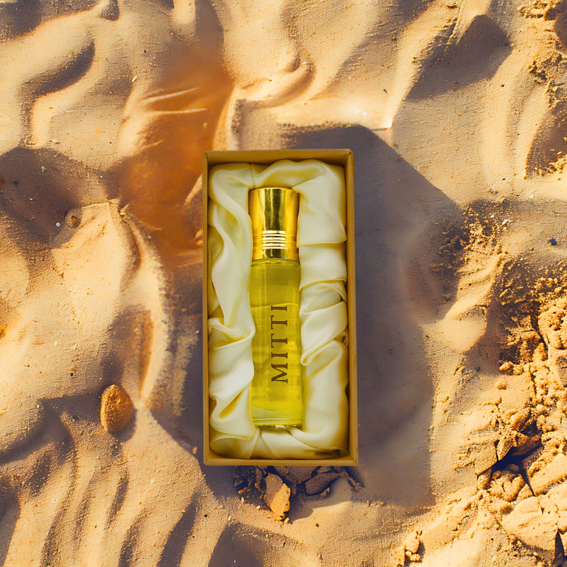 Tatha Mitti Attar in an open box, featuring a 10ml glass bottle with golden cap, placed in a natural mitti (earthy) setting.