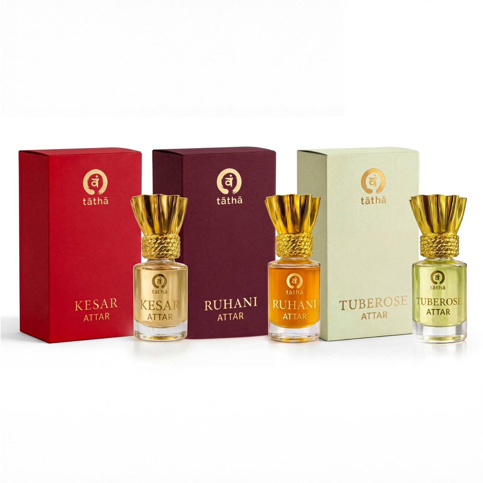 Three attar bottles with gold caps and different colored liquids, each in front of a matching colored box, on a white background.
